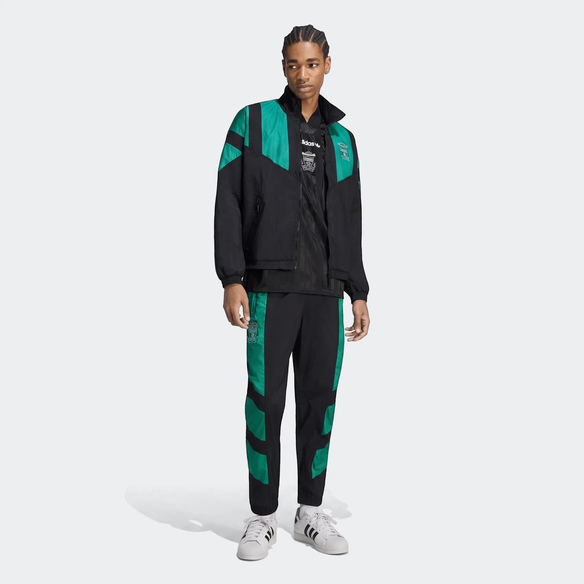 Male model wearing a black and green Adidas Liverpool FC EQT Track Top and matching track pants, with white Adidas sneakers.