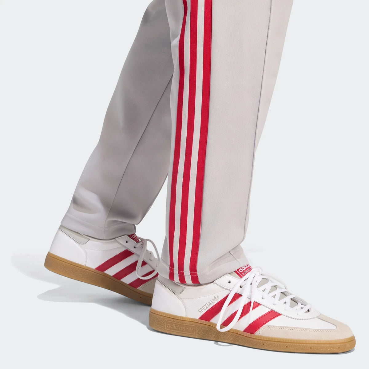 Grey Liverpool Fc Originals track pants with red stripes and white Adidas Spezial sneakers with red accents and gum soles on
