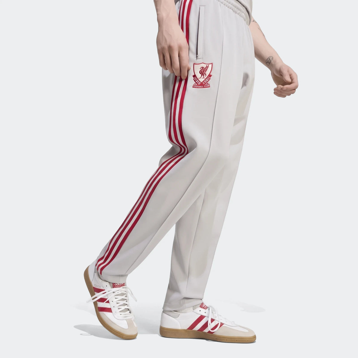 Men's light grey Liverpool FC Originals Track Pants with bold red side stripes and an embroidered club crest, worn with