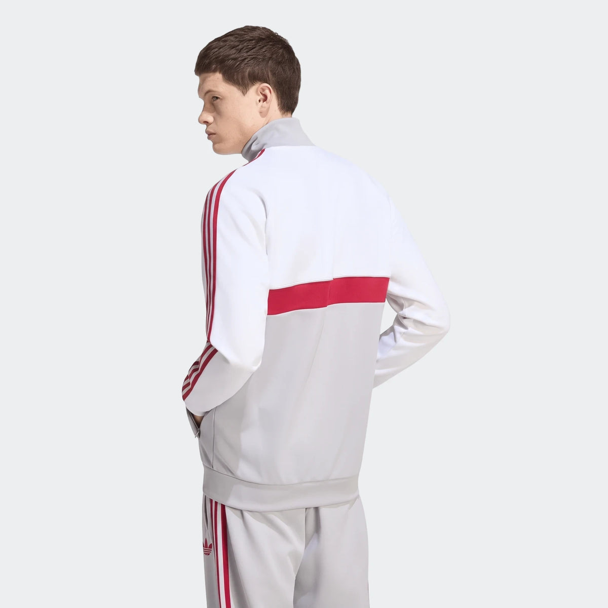 Male model wearing a Liverpool FC Originals Track Top in white and grey with red three-stripes, shown from the back view.