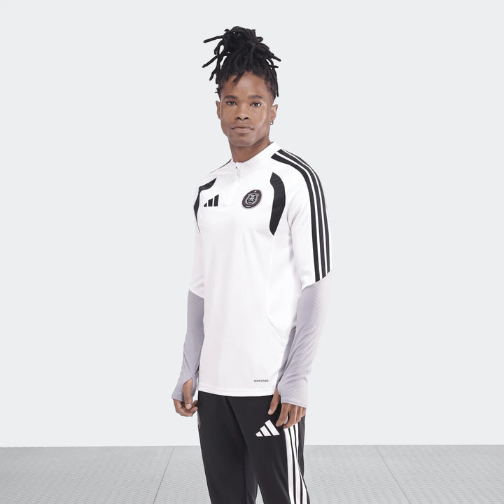 Male model wearing an Adidas Op Tiro26C Top in white with black and gray accents, paired with black Adidas track pants. He