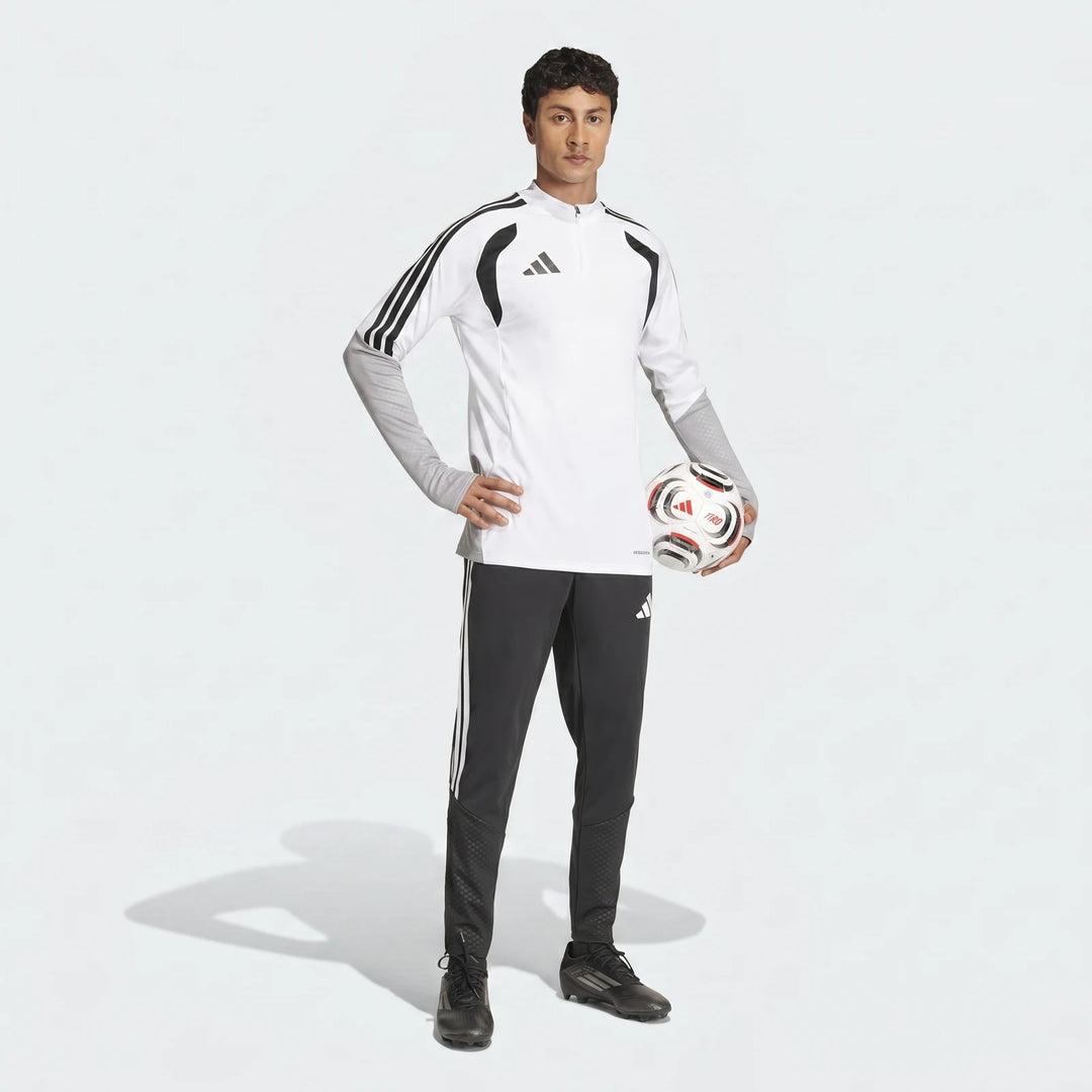 Male model wearing black Adidas Tiro 26 Competition Training Pants and a white long-sleeve top, holding a soccer ball.