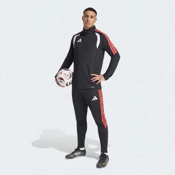 Male model wearing black and red Adidas Tiro 26 League training tracksuit with white accents, holding a white football.