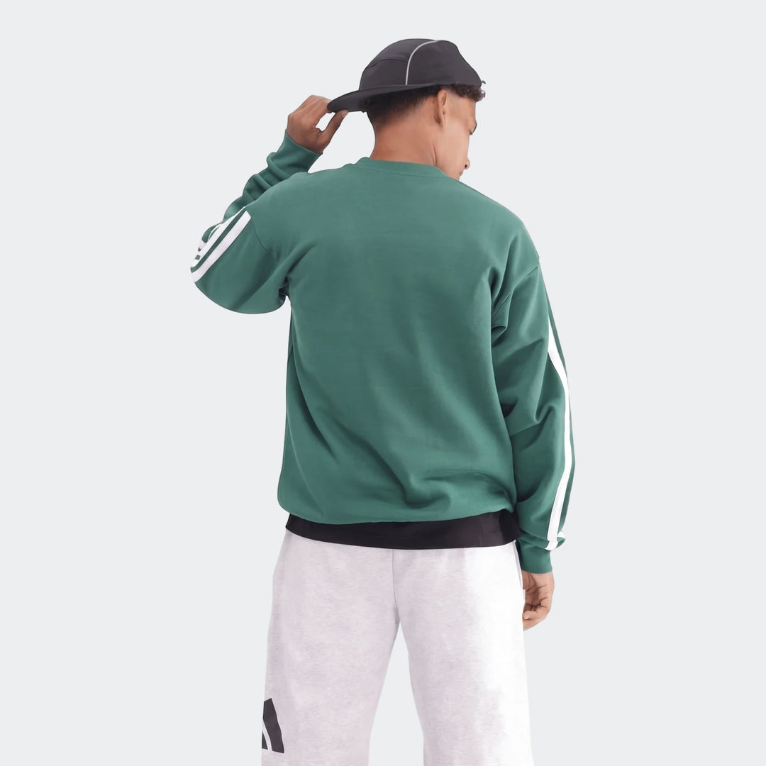 A male model from behind wearing a green crewneck sweatshirt with white stripes on the sleeves and light grey shorts.