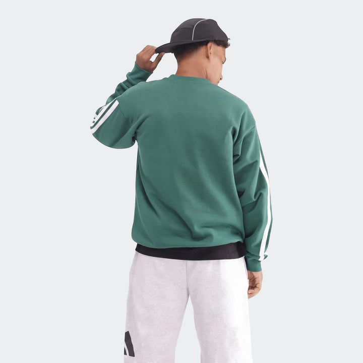 A male model from behind wearing a green crewneck sweatshirt with white stripes on the sleeves and light grey shorts.
