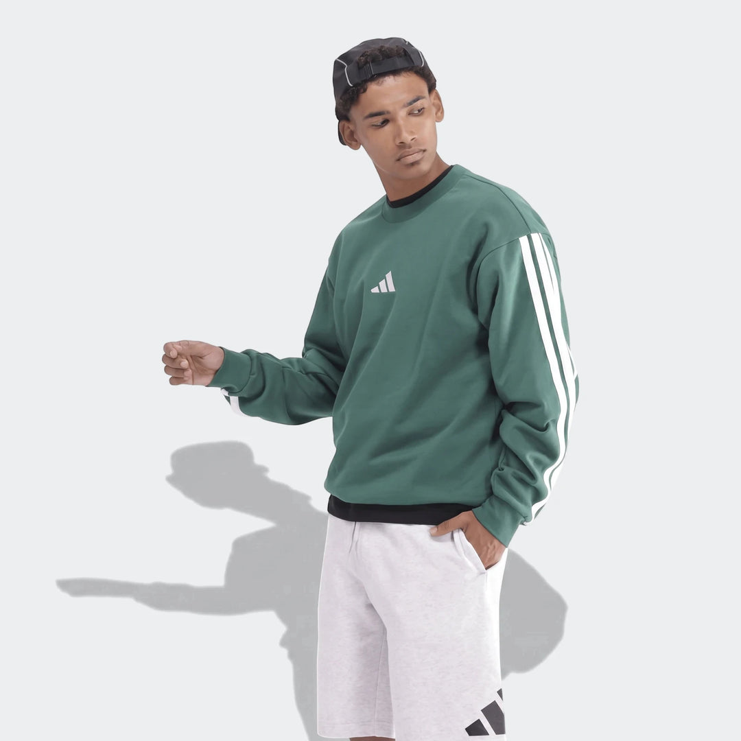 Male model in a green sportswear sweatshirt with white stripes and grey athletic shorts, shown in a side profile.