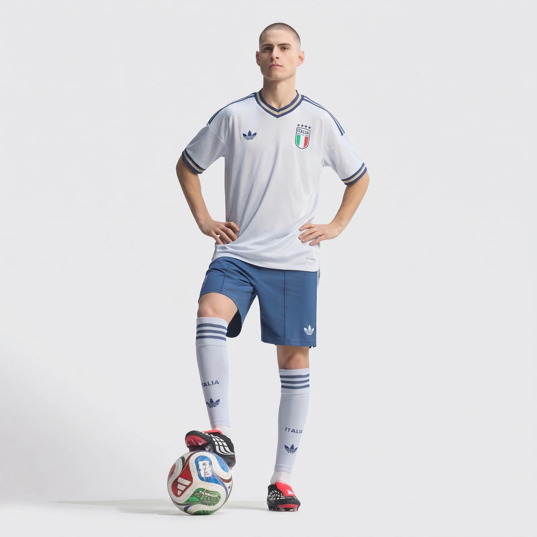 Male model wearing a white and blue Italia soccer jersey, blue shorts, and socks, standing with a soccer ball.