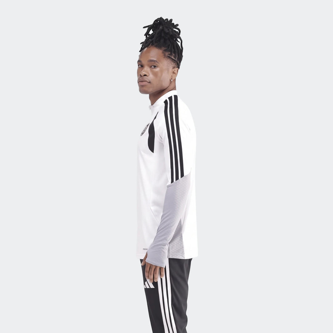 Male model wearing a white Adidas Tiro26C Top with black stripes and gray patterned sleeves, paired with black track pants,