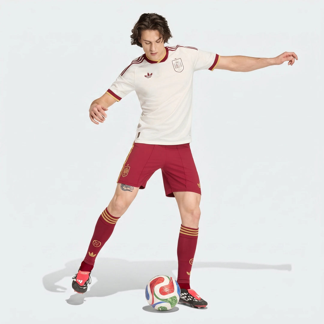 Male model wearing a full white and red soccer uniform, including a short-sleeve jersey, shorts, and socks, posing with a