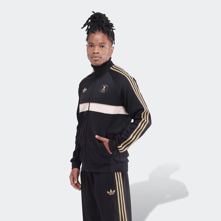 Man wearing a black and gold Adidas Op Og2 Tt track jacket and matching track pants, with an Orlando Pirates FC crest.