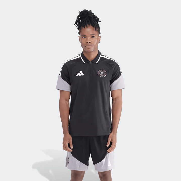 Full body shot of a man wearing a black and grey Adidas Op Tiro26C polo shirt with matching shorts, showcasing the sporty