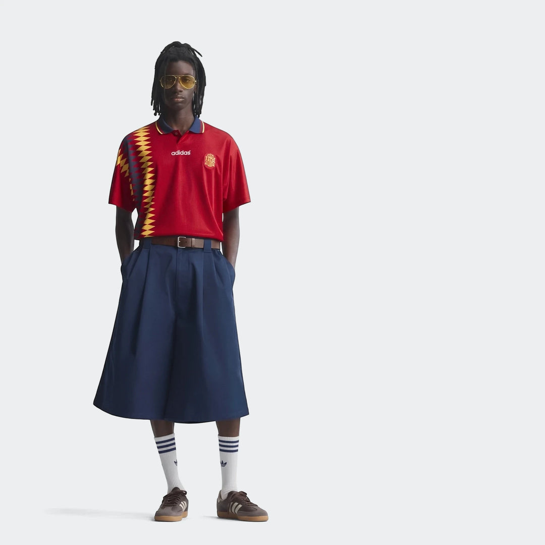 Man wearing a red Z.N.E. Track Top, navy culottes, and brown sneakers in a full body studio shot.