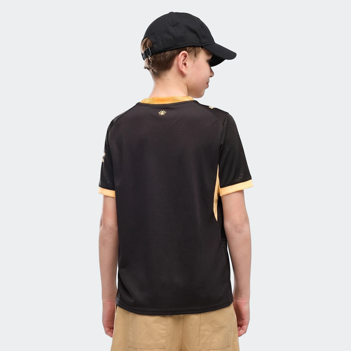 Youth Manchester City 26/27 Away Jersey in black and yellow, shown on a boy from the back with a black cap.