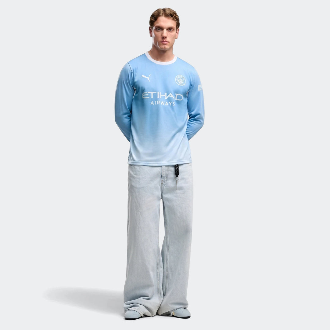 Men's Manchester City 26/27 home long sleeve light blue gradient jersey, worn by a model with wide-leg jeans.