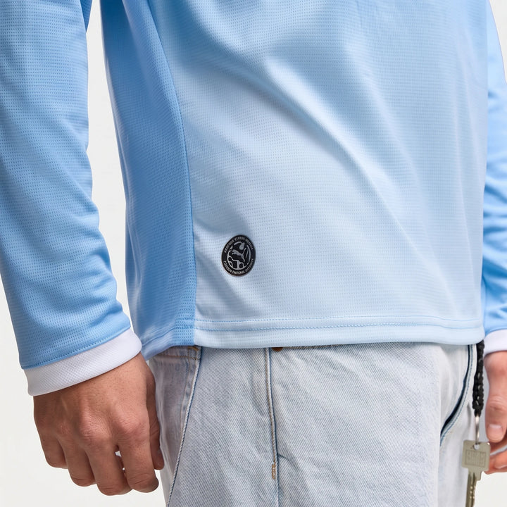 Side view of a man wearing a light blue Manchester City 26/27 Home Long Sleeve Jersey, featuring a textured fabric and a