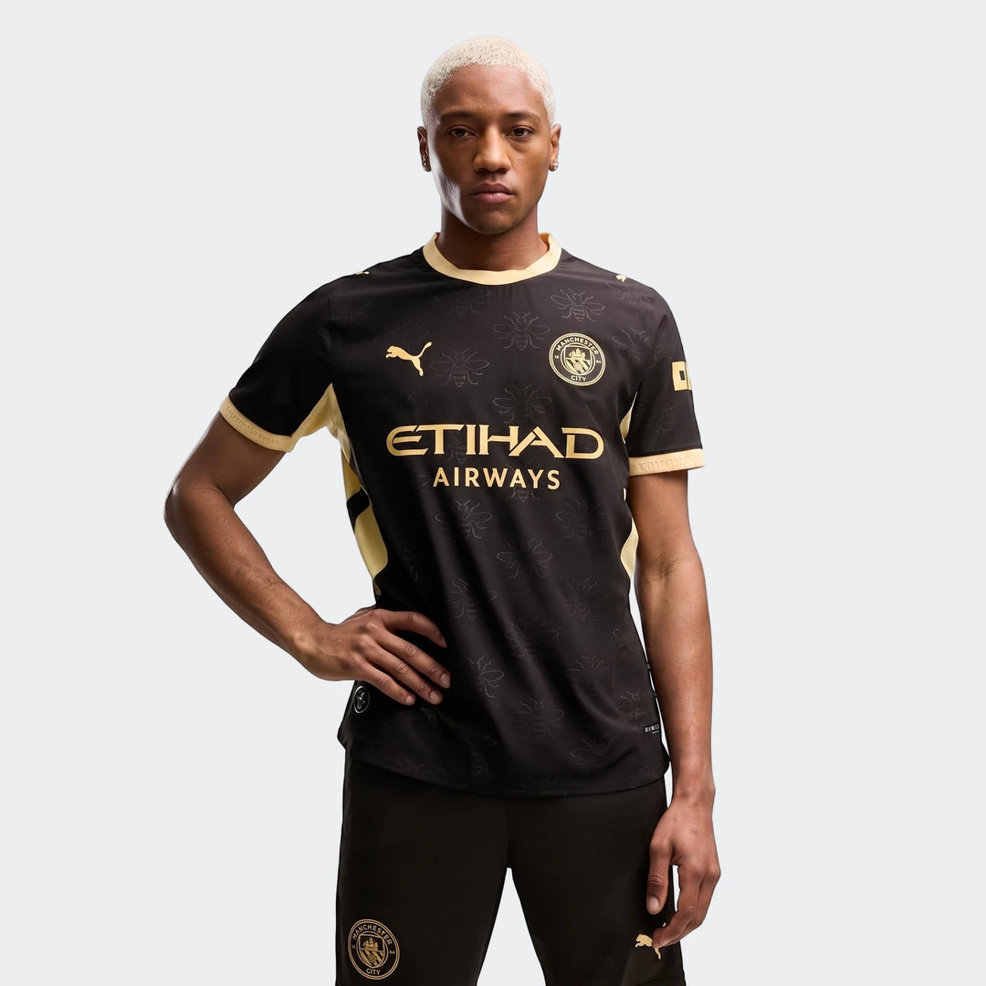 Male model wearing a black and gold Manchester City Away Authentic Jersey for men with matching shorts, shown in a standing