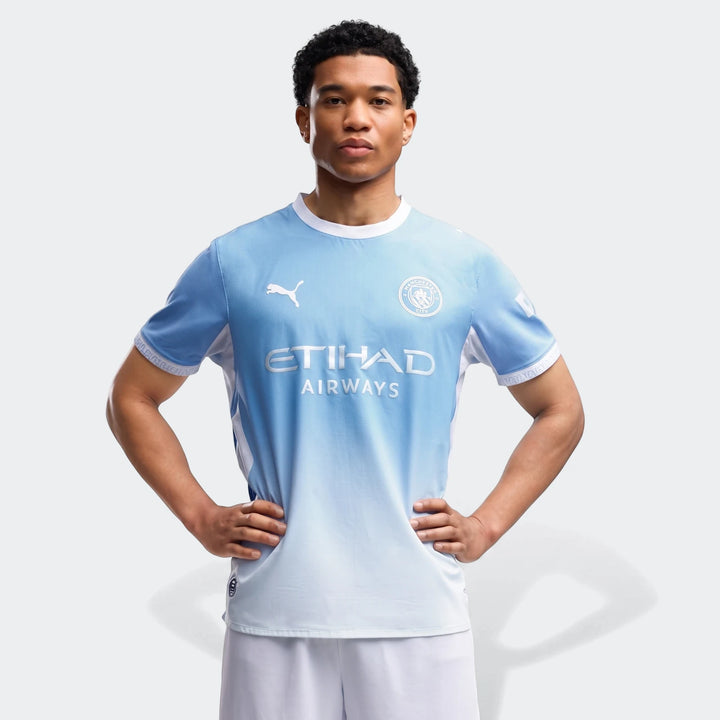 Front view of a male model wearing a light blue and white gradient Manchester City Home Authentic Jersey, featuring club
