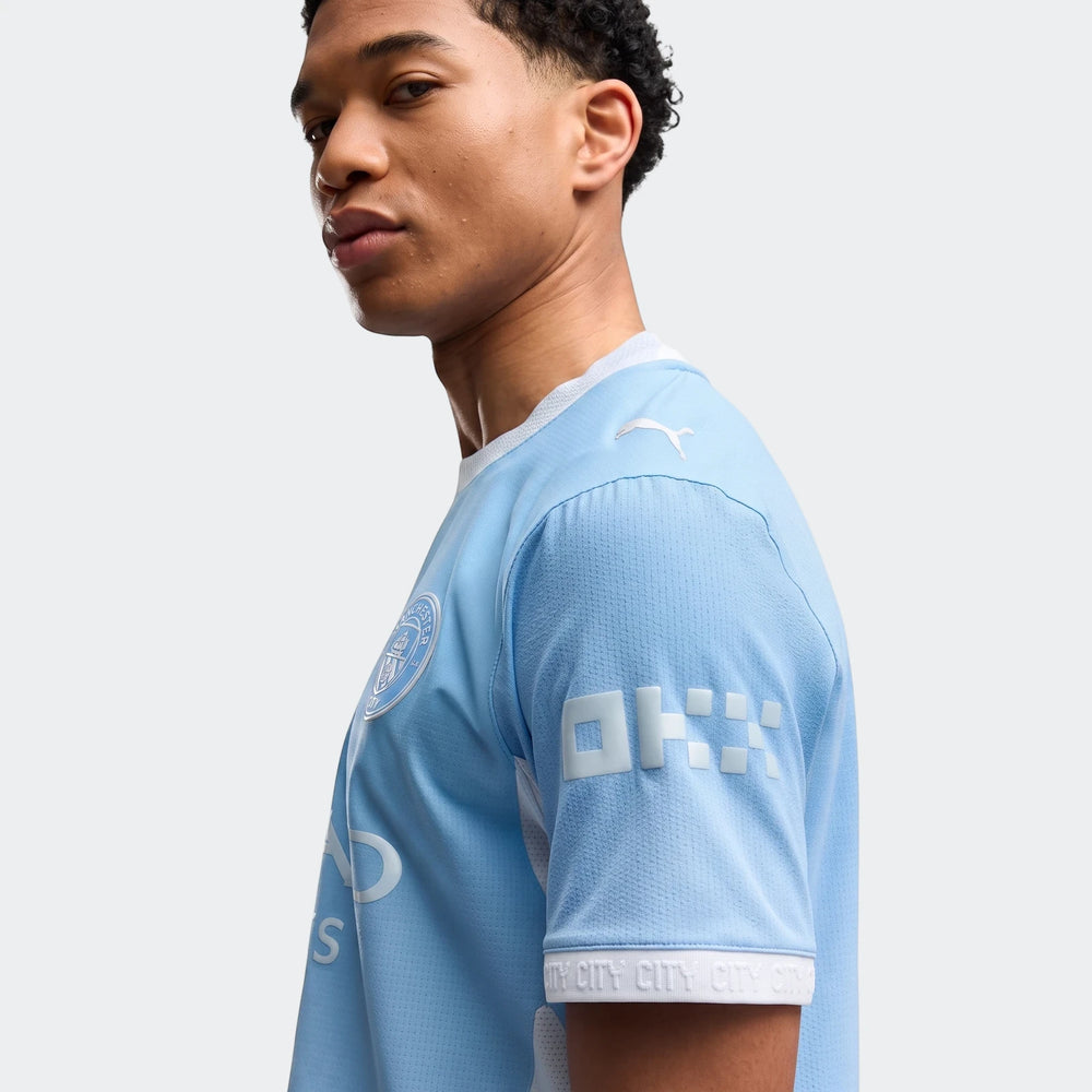 A man models the light blue Manchester City Home Authentic Jersey for men, featuring club crest and sponsor logos.
