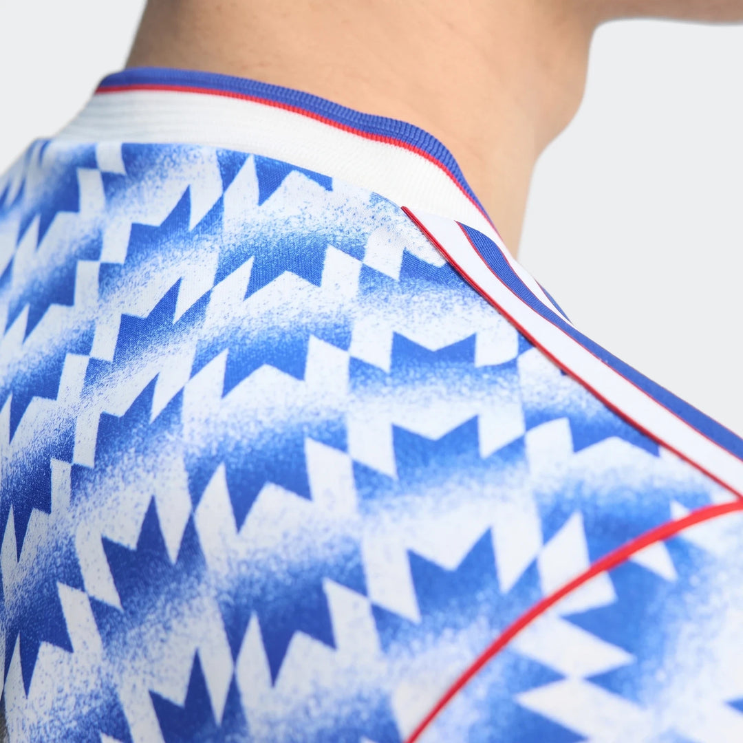 Manchester United 1990 Away Jersey close-up showing blue and white geometric print with red trim at the collar.