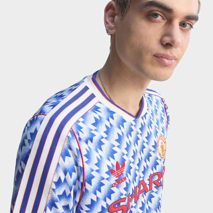 Manchester United 1990 Away Jersey in blue and white geometric print with red stripes, front view.