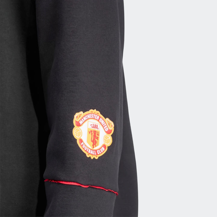 Manchester United 1990 sweatshirt in black, close-up sleeve with Manchester United crest patch and red cuff trim.