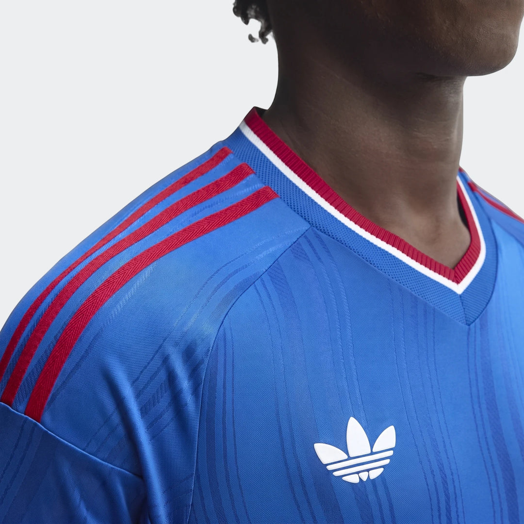 Close-up of a person wearing a blue Manchester United 26/27 Away Authentic Jersey Longsleeve with red stripes and white