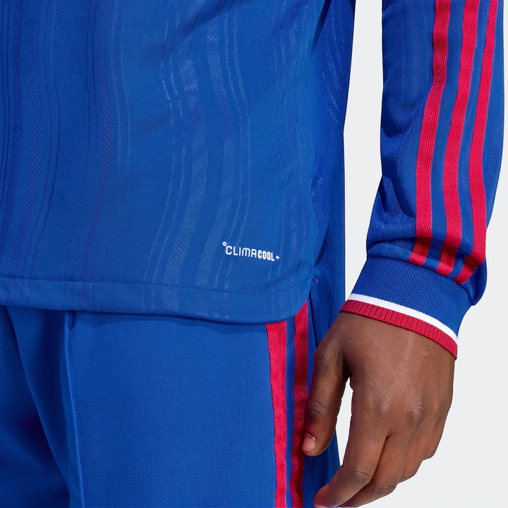 Close-up of a Manchester United 26/27 Away Authentic Jersey Longsleeve in blue with red stripes, worn by a person, showing