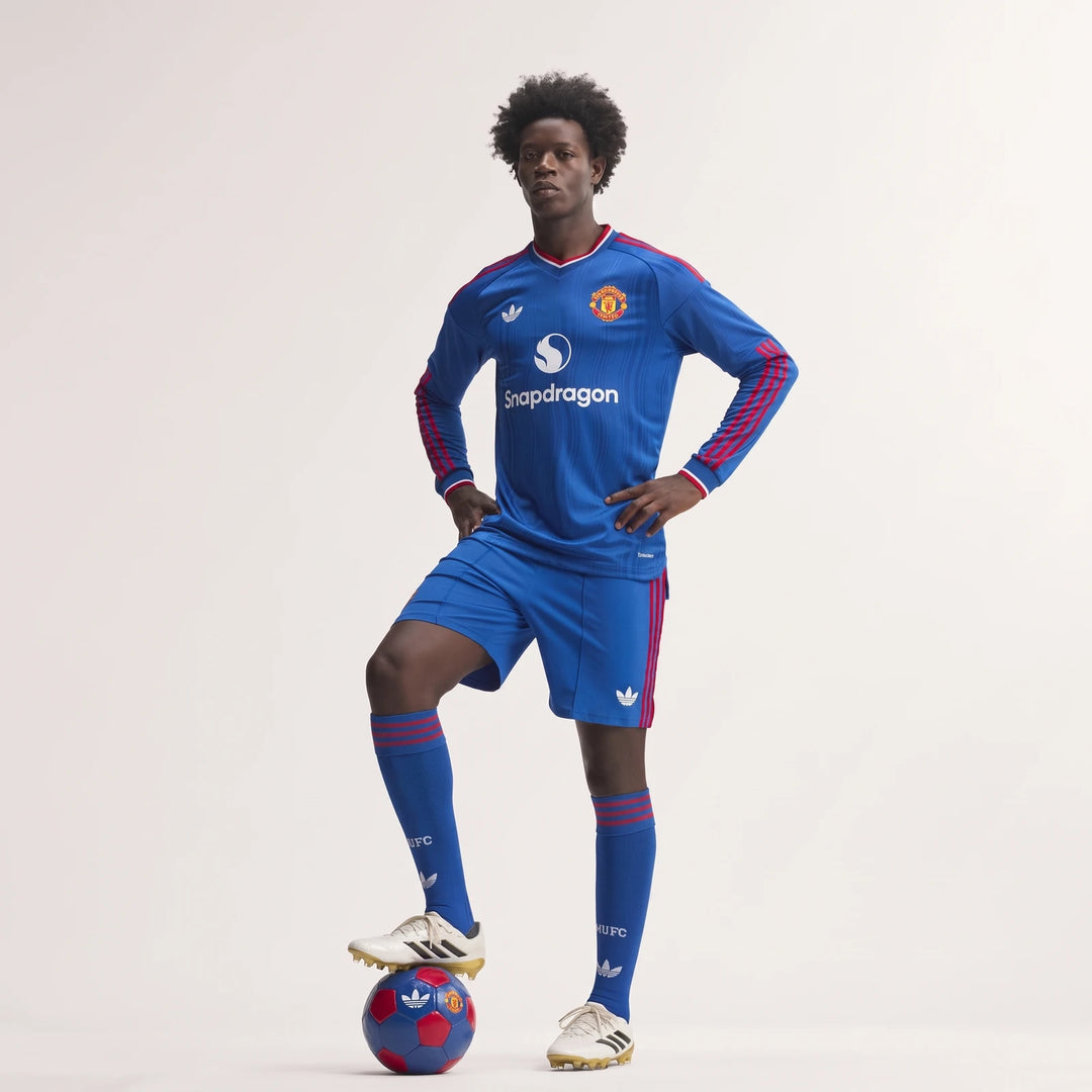 Male model wearing a blue Manchester United 26/27 Away Authentic Longsleeve Jersey, matching shorts, and socks, with a