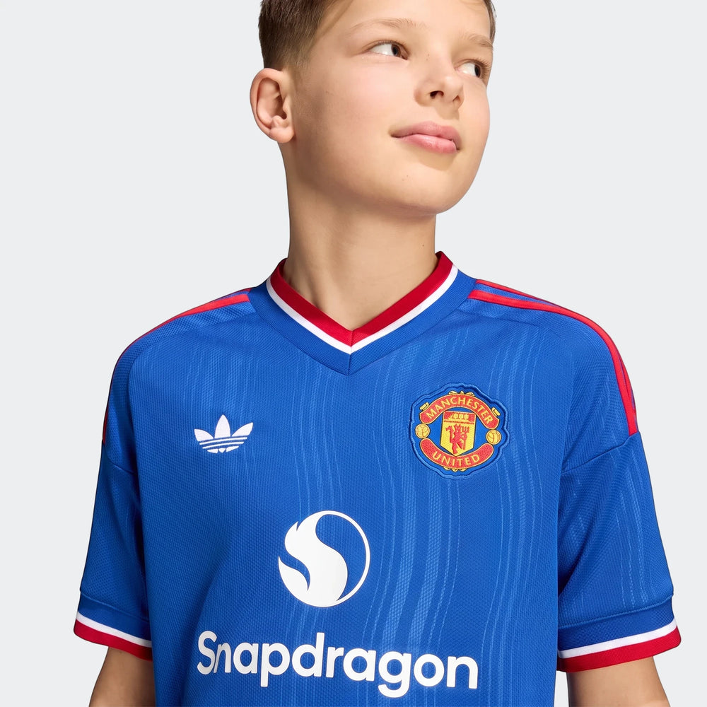 Close-up of a boy wearing the blue Manchester United 26/27 Away Jersey for kids, featuring sponsor and club crest.