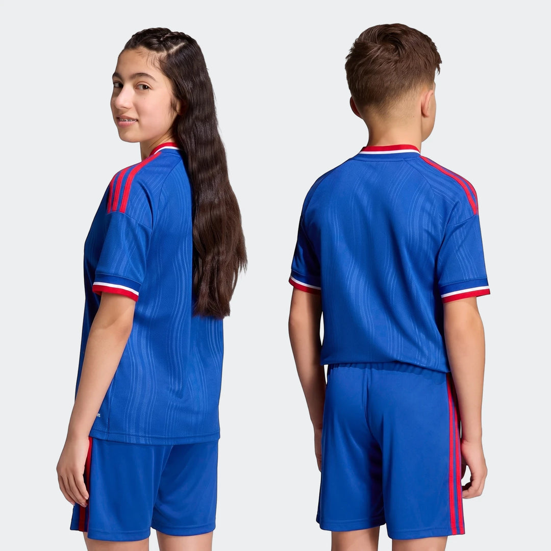 Manchester United 26/27 Away Jersey Kids in blue, featuring matching shorts and red stripes, modeled by a boy and girl.