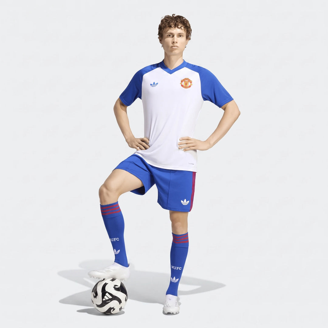 Male model wearing Manchester United 26/27 Pre Match Jersey, white and blue, with matching shorts and socks, posing with a