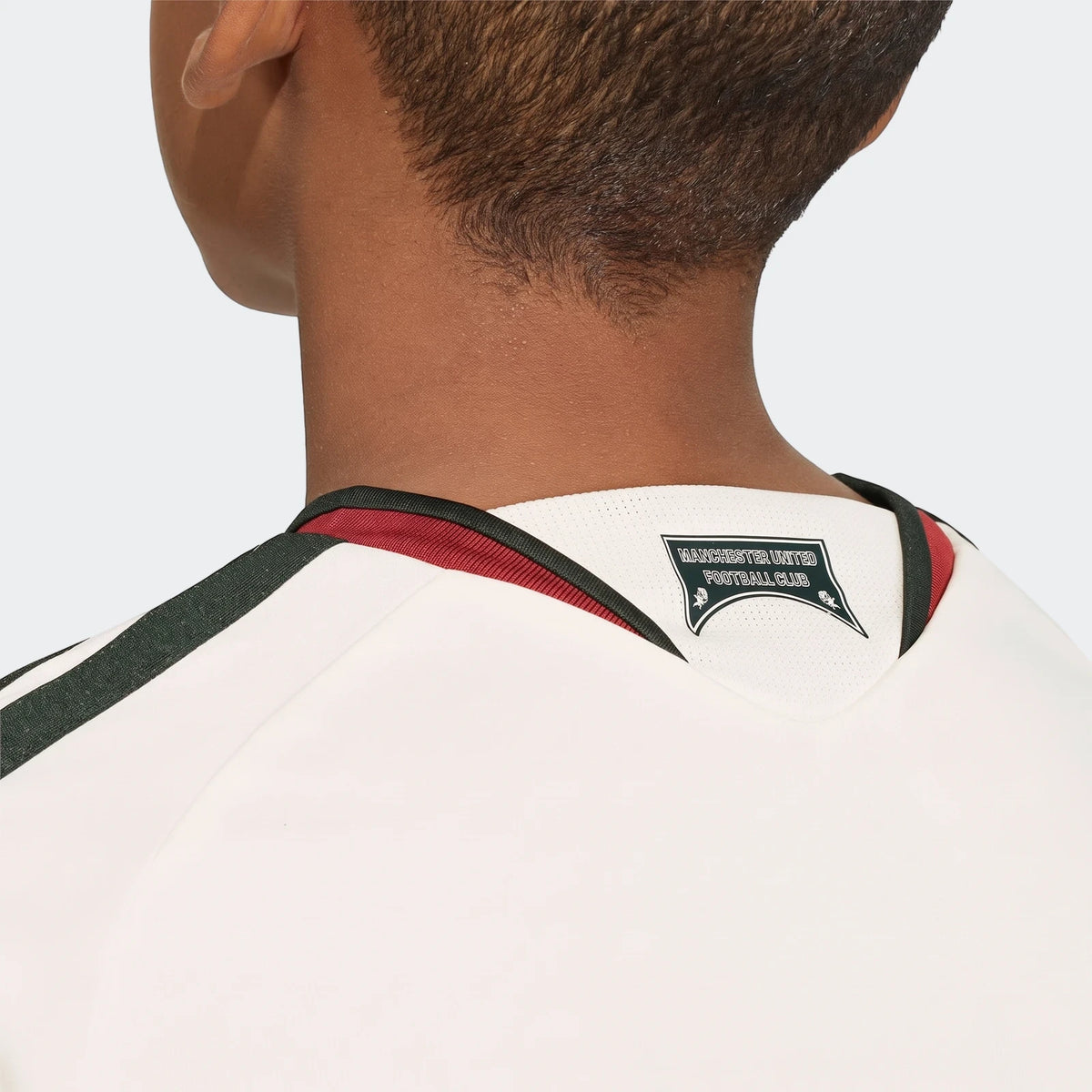 Close-up of the back of a child wearing the off-white Manchester United 26/27 Third Jersey with striped collar and visible