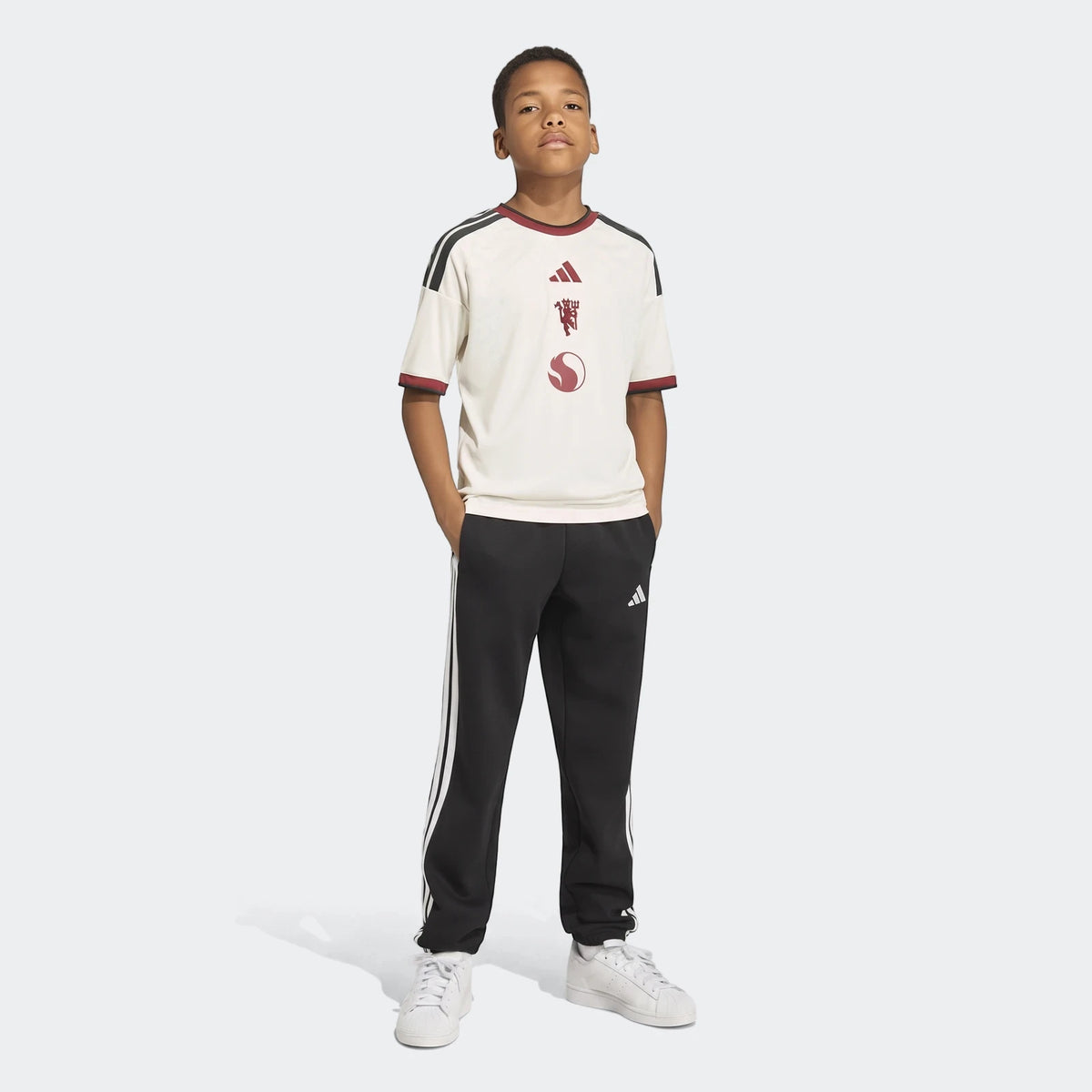 Kids Manchester United 26/27 Third Jersey on a young boy, paired with black Adidas track pants and white sneakers.
