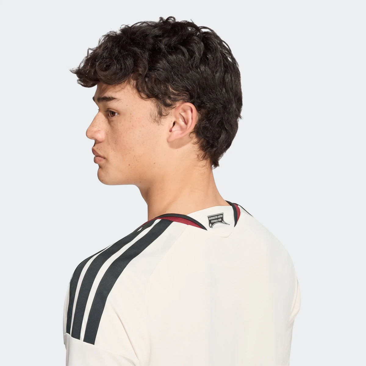Manchester United 26/27 Third Jersey on a male model, featuring white fabric with black shoulder stripes, shown from the