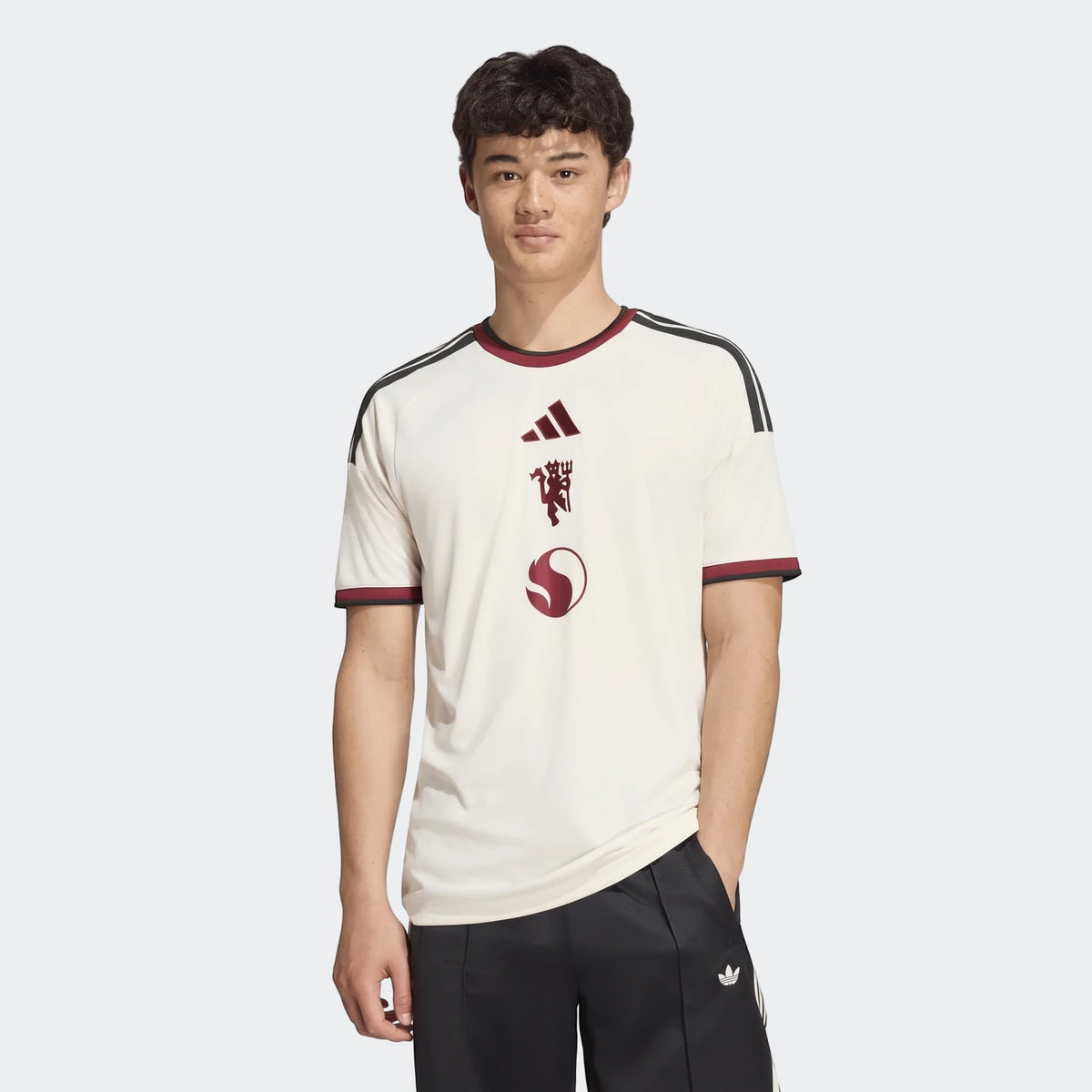 Male model wearing an off-white Manchester United 26/27 Third Jersey with dark red Adidas, devil, and S-shaped logos, and