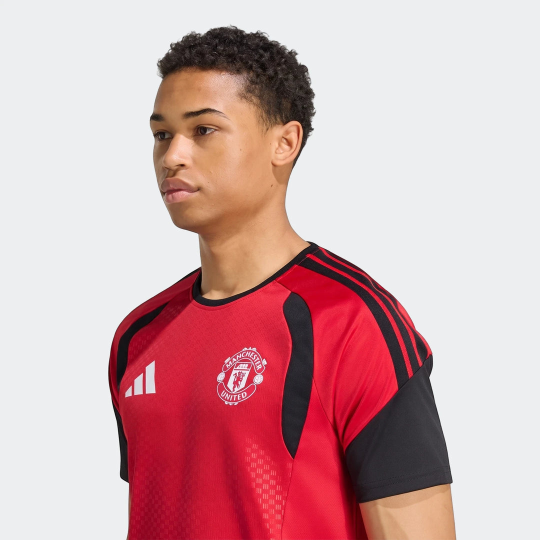 Male model in a red and black Manchester United 26/27 Tiro Training Jersey, with club crest and Adidas logo, studio shot.