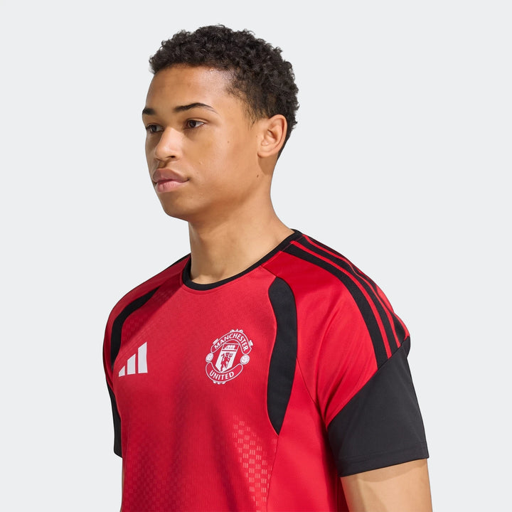 Male model in a red and black Manchester United 26/27 Tiro Training Jersey, with club crest and Adidas logo, studio shot.
