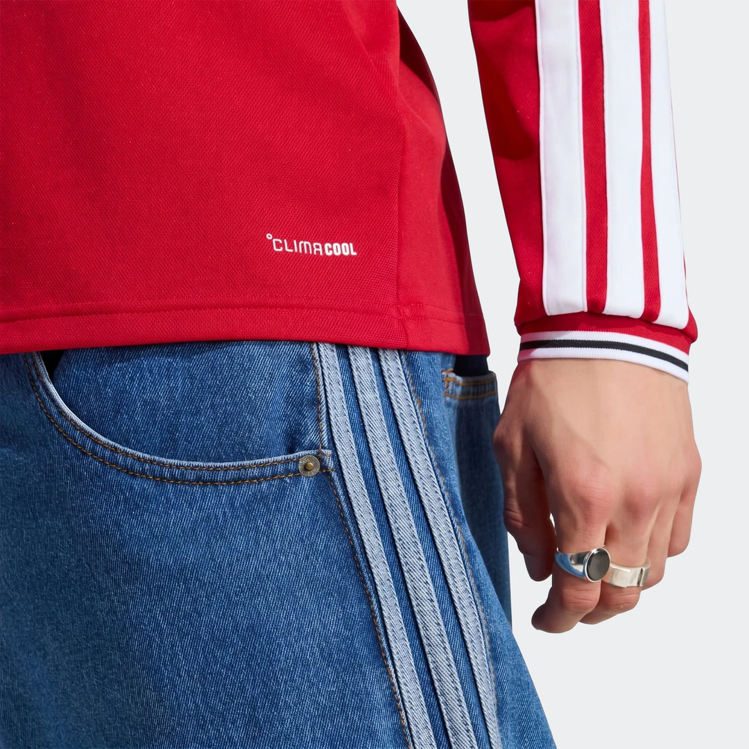 Close-up of Manchester United 26/27 long sleeve home jersey in red with white sleeve stripes and ribbed cuff.
