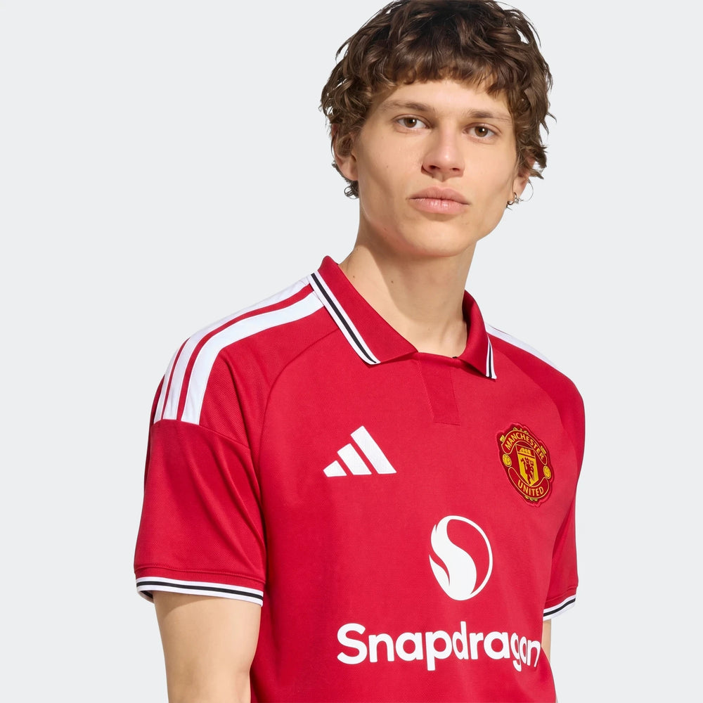 Manchester United 26/27 Home Jersey in red with white shoulder stripes, polo collar, and club crest, front view.