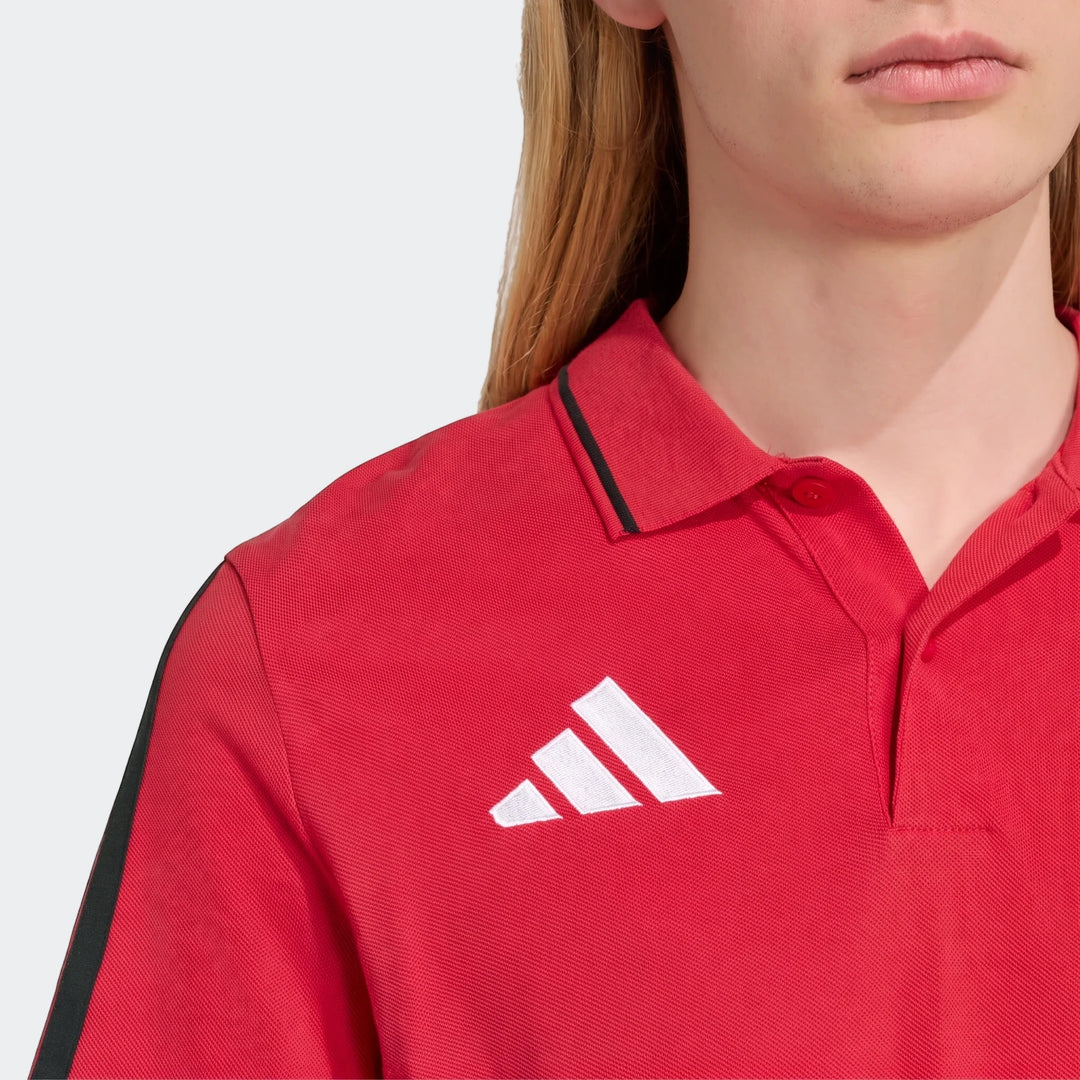 Close-up of a person wearing a red Adidas Manchester United Dna Polo Shirt, featuring a black collar stripe and white logo.