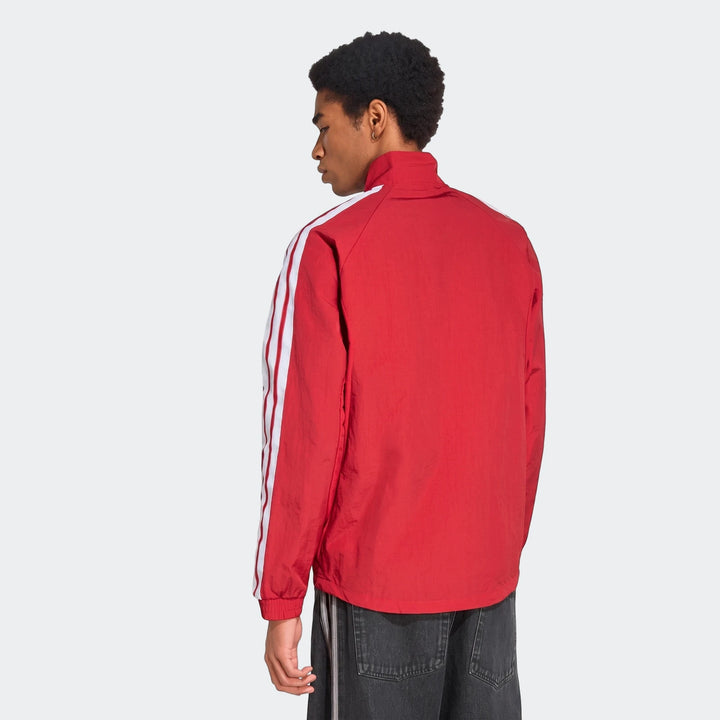 Rear view of a model wearing the red Manchester United Home Anthem Jacket with white stripes on the sleeves.