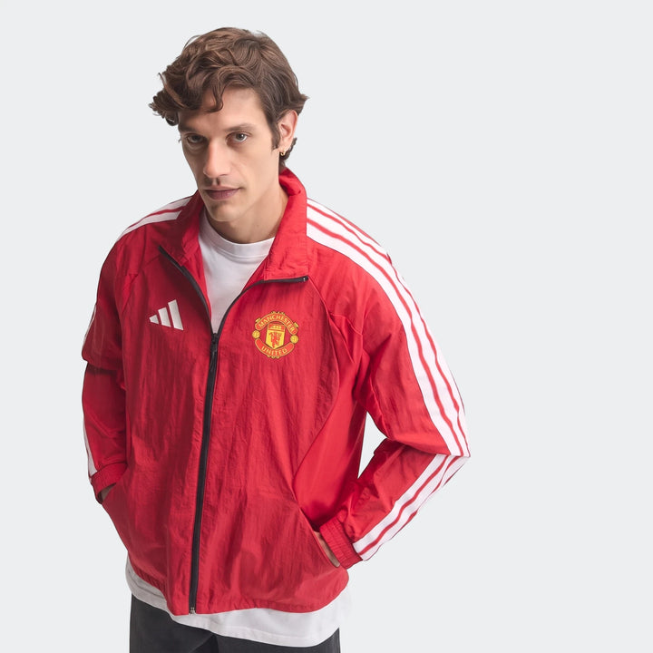 Male model wearing a red Adidas Manchester United Home Anthem Jacket, featuring white stripes on the sleeves and official