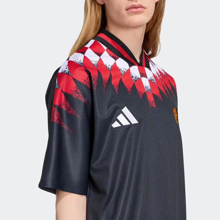Manchester United Street Jersey in black with red and white geometric shoulder pattern and ribbed V-neck collar.