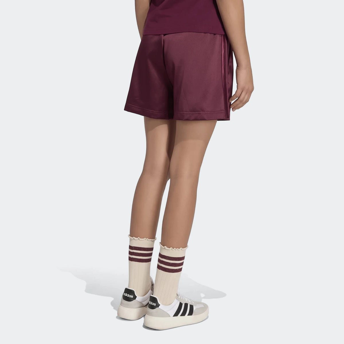 Maroon satin shorts with side stripes worn by a person, seen from behind, styled with cream and maroon striped socks and
