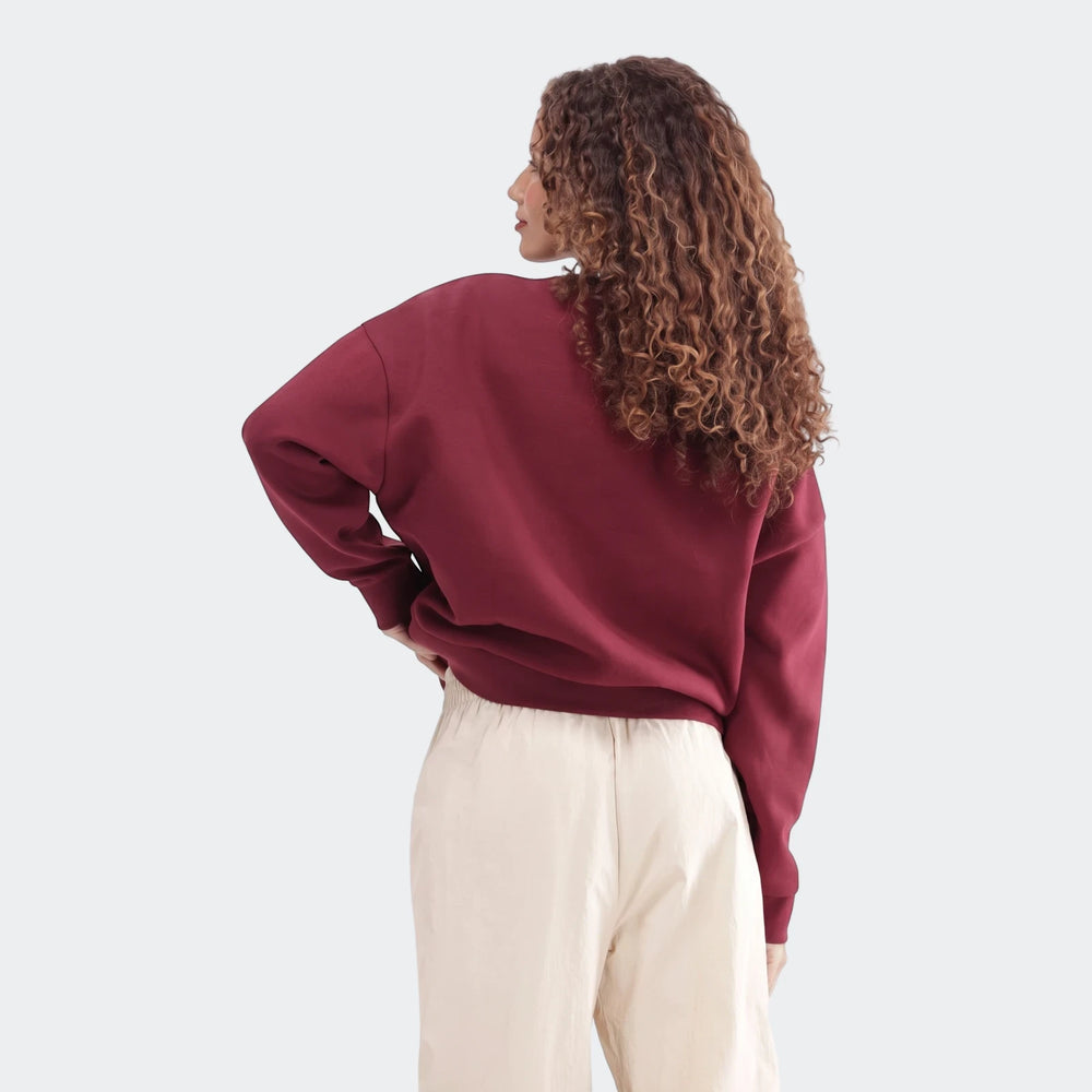 Woman wearing a maroon Slim Fleece Crew Sweatshirt with curly hair and light pants, viewed from the back.