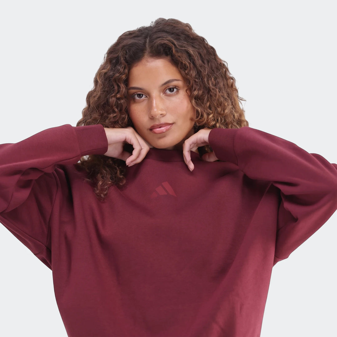 Close-up front view of a woman with curly hair showcasing a maroon Slim Fleece Crew Sweatshirt, highlighting the fabric and