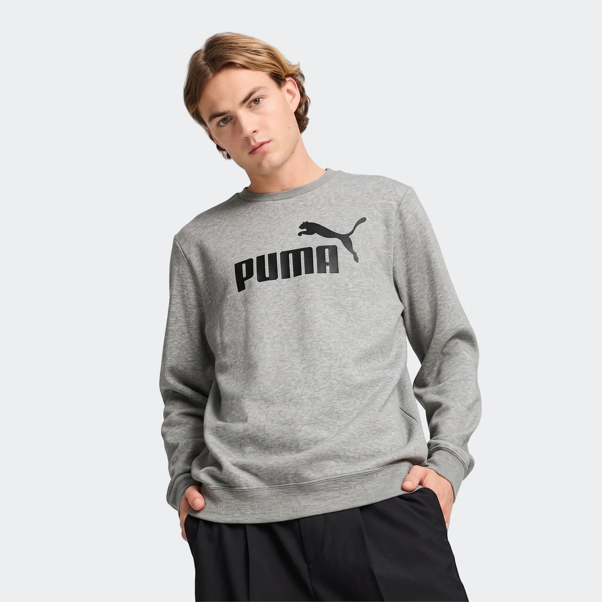 Men's grey Puma Ess No.1 Logo crewneck sweatshirt featuring a black logo on the chest, modeled from the waist up.