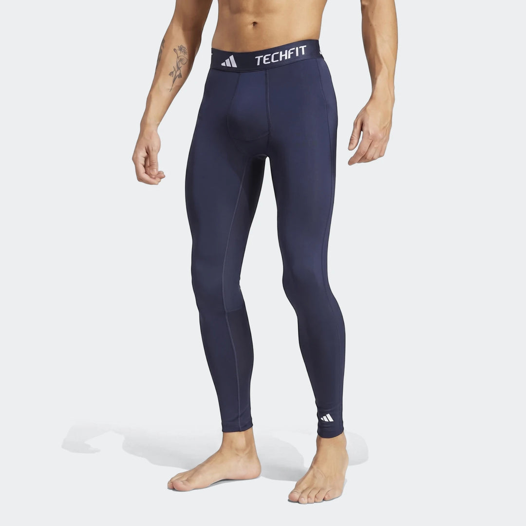 Man wearing navy blue Adidas Techfit Football Base Layer Tights, shown in a full body view.