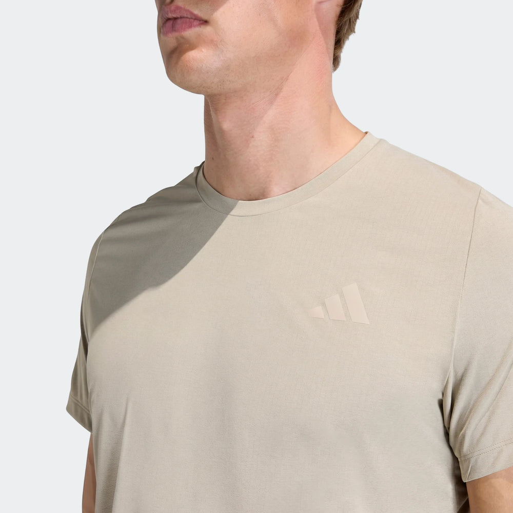 Close-up of a men's light beige Adi365 T-shirt with a subtle Adidas logo, worn by a model.