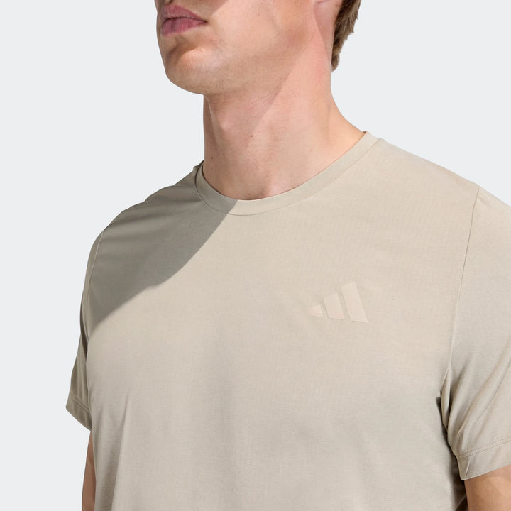 Close-up of a men's light beige Adi365 T-shirt with a subtle Adidas logo, worn by a model.